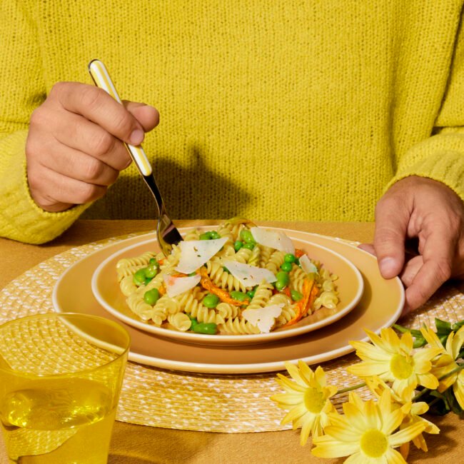 a yellow world with a person holding a fork in a plate of spaghetti